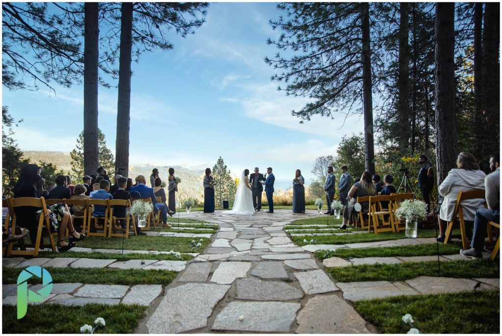 Forest house lodge ceremony location with bride and groom facing each other saying their vows overlooking the sierra mountains.